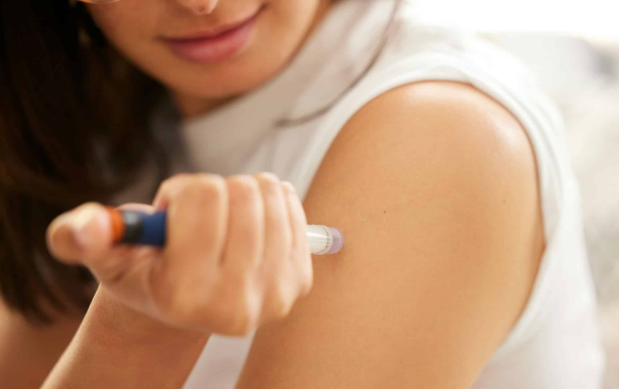 Closeup shot of an unrecognizable woman injecting herself in the arm with insulin at home